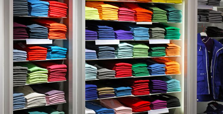 bunte T-Shirts liegen nach Farben sortiert und gefaltet im Regal...