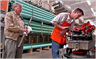A Home Depot employee cuts pipe for a customer. The chain will close 15 stores...