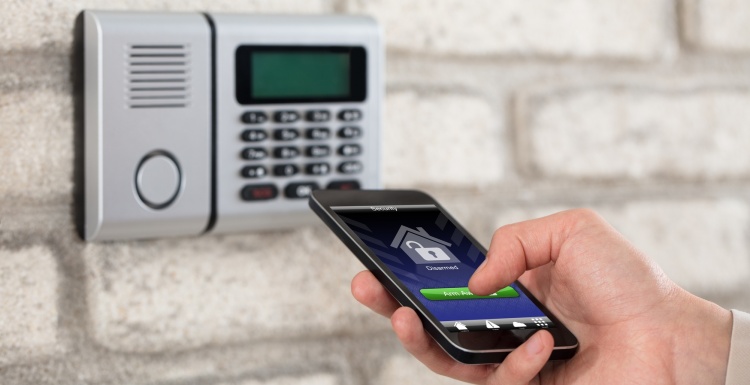 Person with smartphone at a keypad of an alarm system; copyright:...