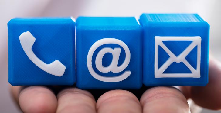 Hand holding little blue blocks with phone, mail and at-icon; copyright:...