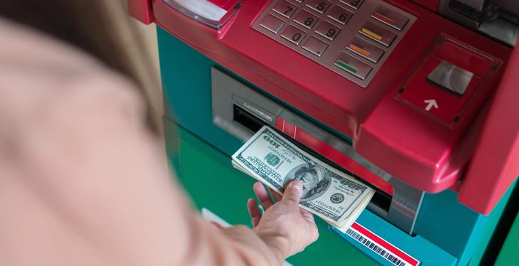 Woman taking bank notes from an ATM; copyright: panthermedia.net/Tzido...