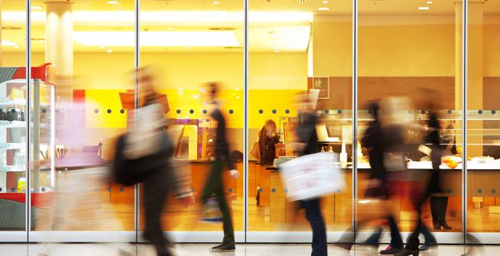 Silhouettes of people walking in front of a glass facade; copyright:...