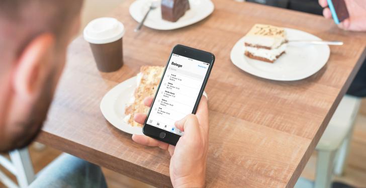 Man holding a smartphone sitting at a table with desserts...