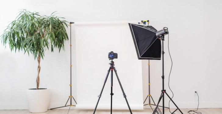 Camera tripod pointing at a white wall.