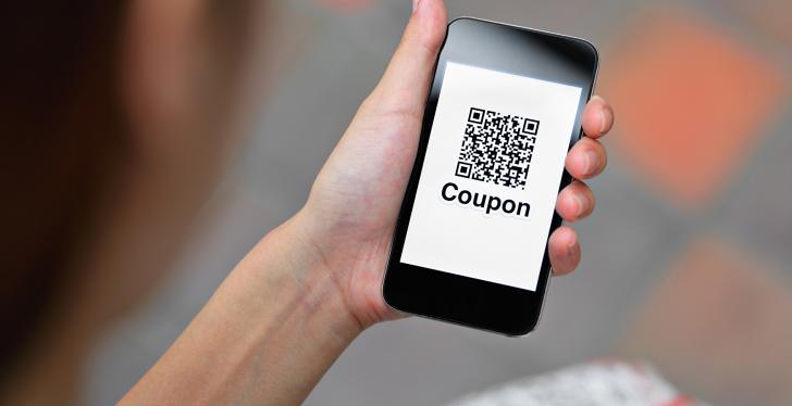 Person holding smartphone with QR code and Coupon on display...