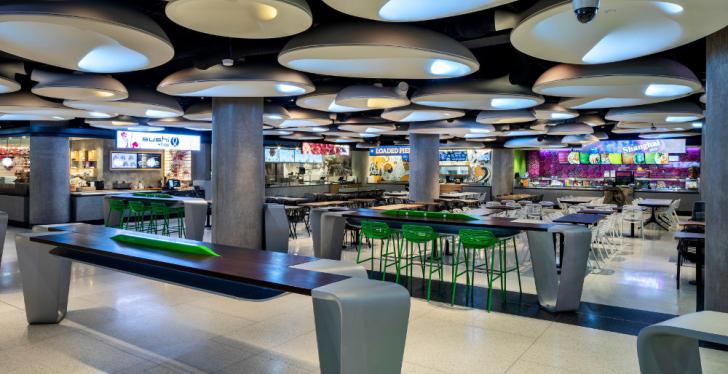 Empty food court with bars and tables and lighting installation at the ceiling;...