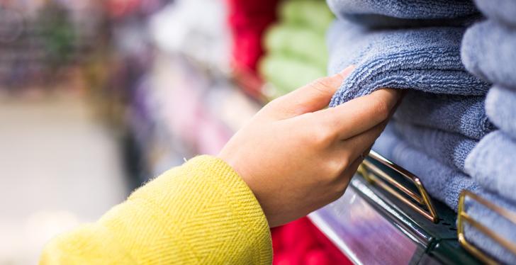 Hand taking a towel out of a stack of towels in a store; copyright:...