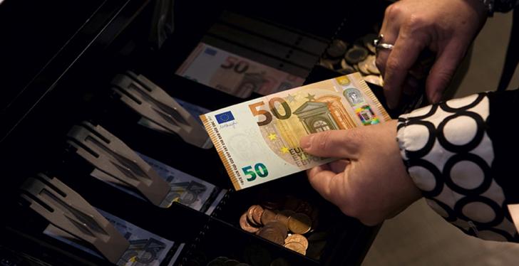 Cash register, woman holding 50 Euro note in her hands...