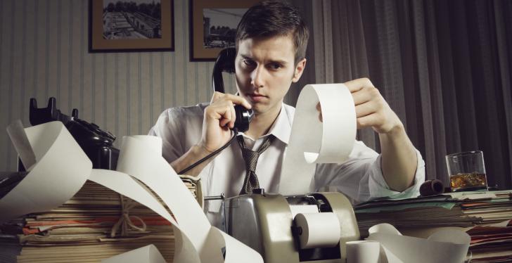 Man at a desk with a bunch of paper vouchers