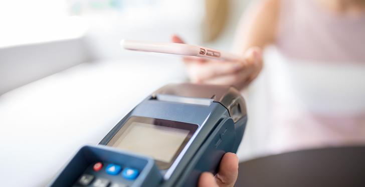 Person holds smartphone over POS terminal