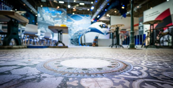 A printed floor in an exhibition hall with the visual of a manhole cover...