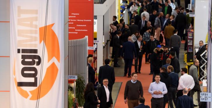 Visitors in an exhibition hall; on the left a logo from the LogiMAT exhibition...