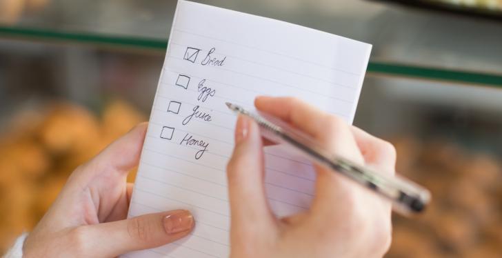 Someone holding a shopping list and a pen in his hand...