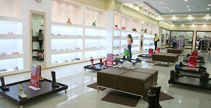 A shop with illuminated product shelves and black leather seating in the middle...