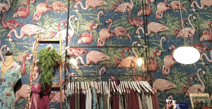 A wallpaper with flamingos, in front: a wardrobe with clothes...