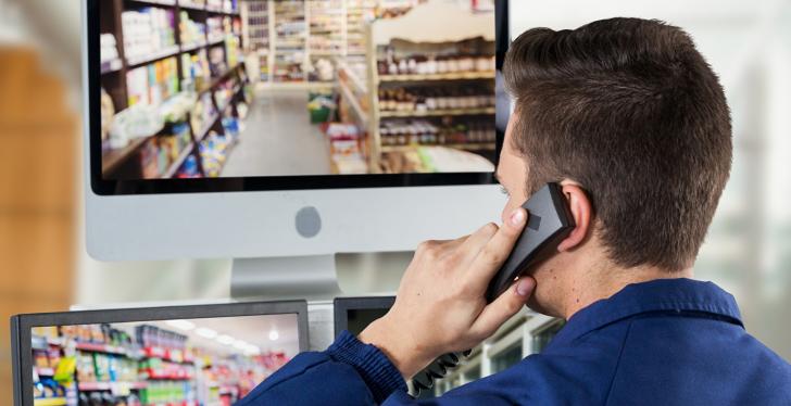 A man looks at a surveillance monitor and makes a phone call...