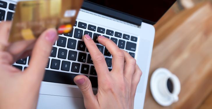 A person holding a mastercard while working on a laptop...