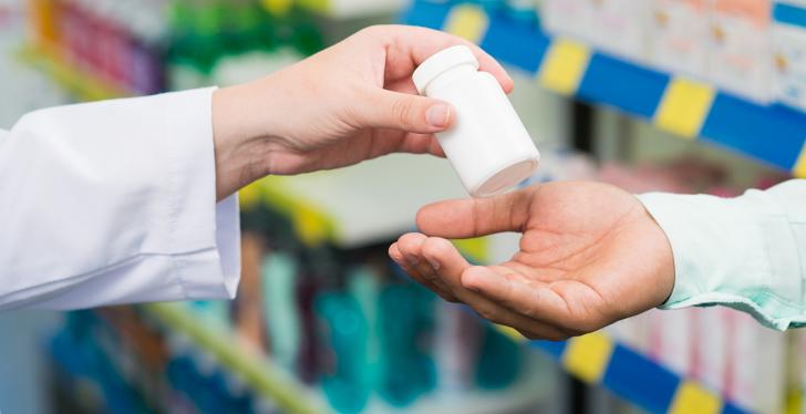 Pharmacist hands a small package of pills to someone...