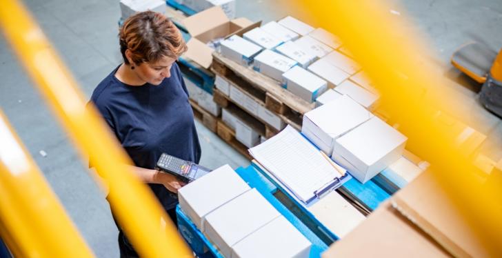 A woman working in a warehouse scanning packages