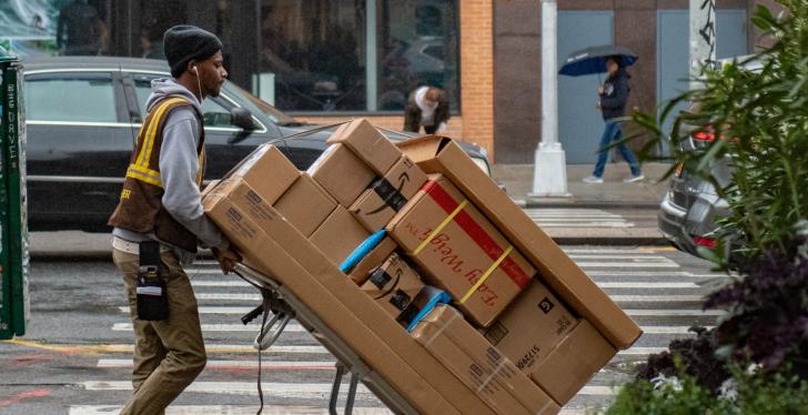 A parcel service employee drives a cart with many parcels along a road...