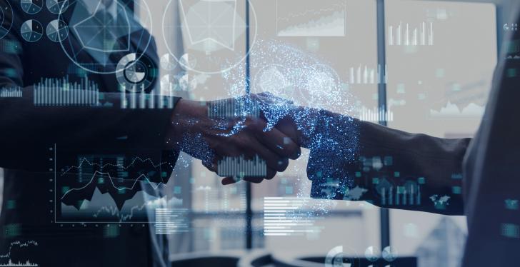 Two people shake hands behind transparent graphics