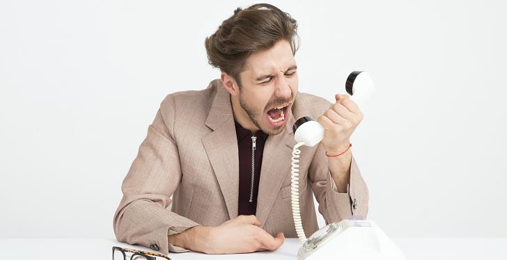 An angry man shouts into a white phone