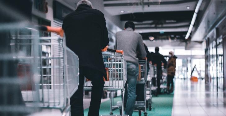 Several people standing in a line with shopping carts...