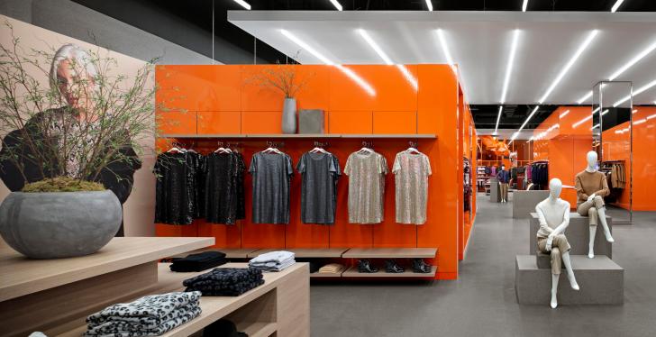 Interior of a flagship fashion store with bright orange furniture and grey...