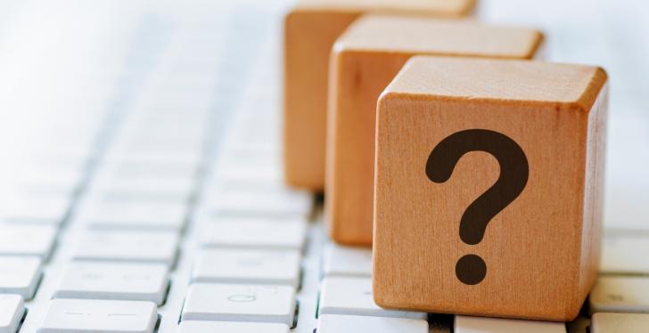 Three wooden dices with question marks on a computer keyboard...