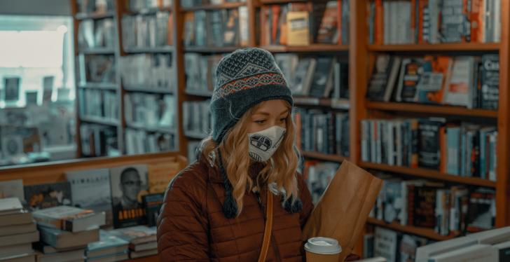 A woman wearing a mask shopping in a book store; copyright: Clay Banks/Unsplash...