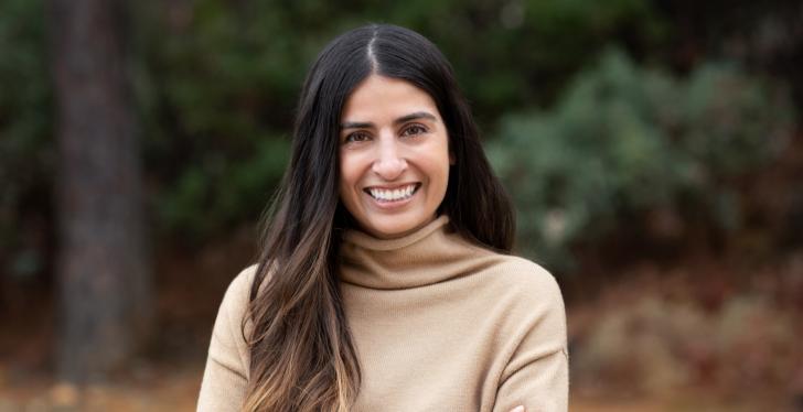 A young woman with long brown hair smiling into the camera...