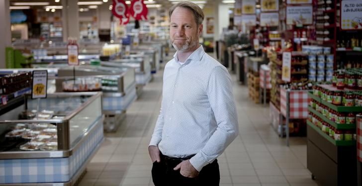 Jesper Due Loevbjerg standing in an aisle within his store...