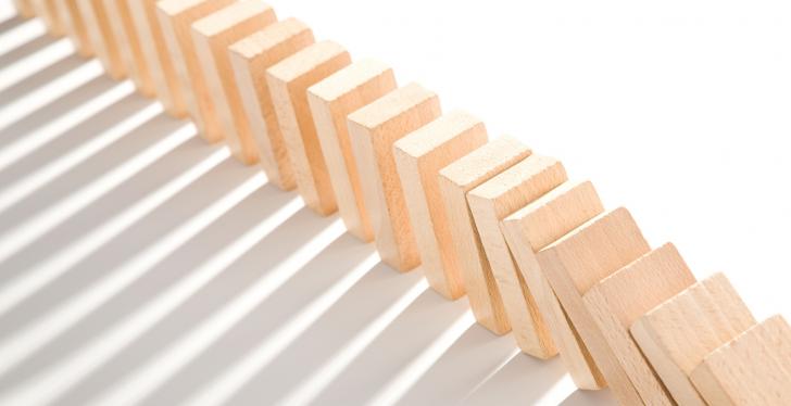 A falling row of wooden dominoes on a white background; copyright:...