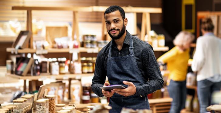 Man With Tablet In Front Of Supermarket Shelf