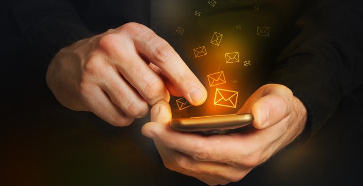 Man in black shirt is typing a text message on his smartphone close up image...