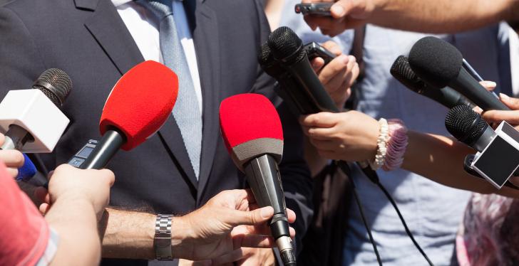 many microphones are pointed at a man who is giving an interview...