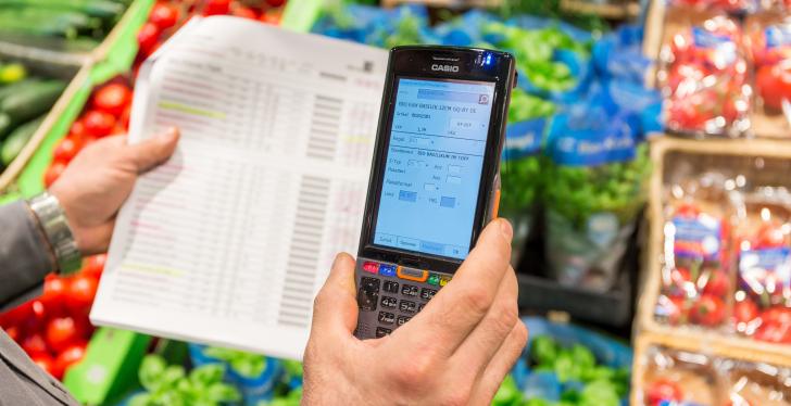 A person is standing in the vegetable department of a supermarket holding a...