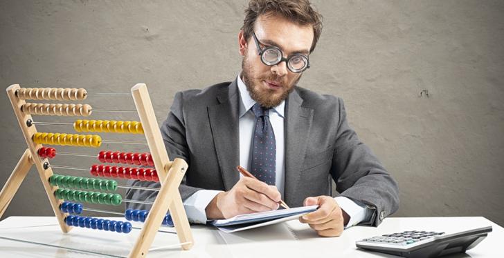 An accountant sits in front of a calculator and an abacus with colored balls;...