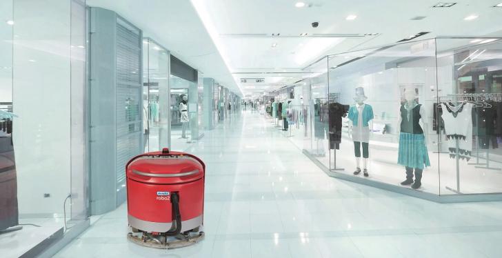 A red self-driving robot cleaning a floor in a retail space; copyright:...