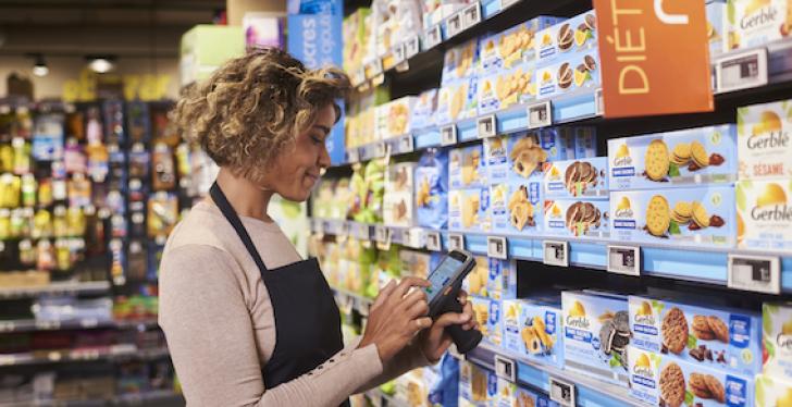 A person is using a handheld scanner in front of a shelf...