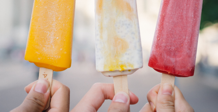 Three hands holding three popsicles