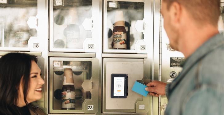 A man holds a payment card to a payment terminal of a vending machine...