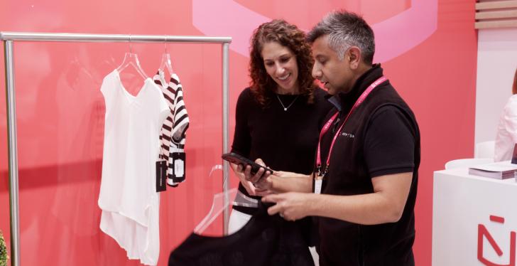 A man is showing a woman something on an iPhone in a fashion store; copyright:...