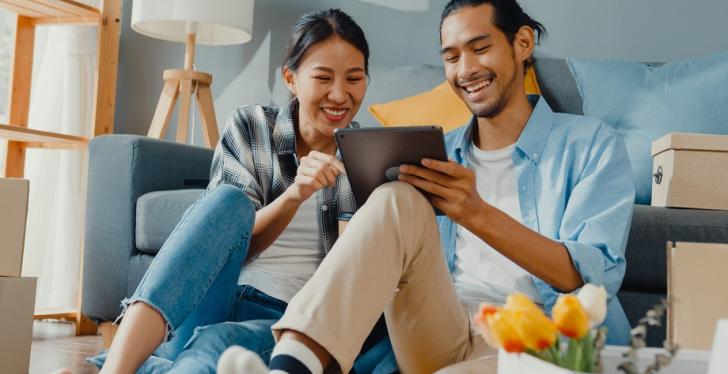 Two people smiling and looking at a tablet