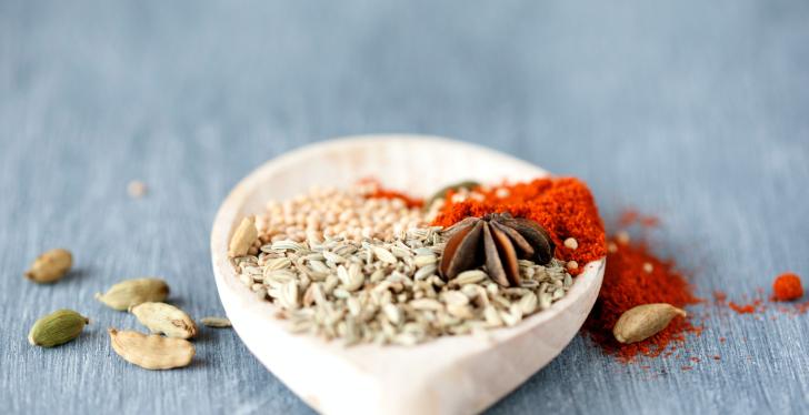 A big wooden spoon with different spices on it