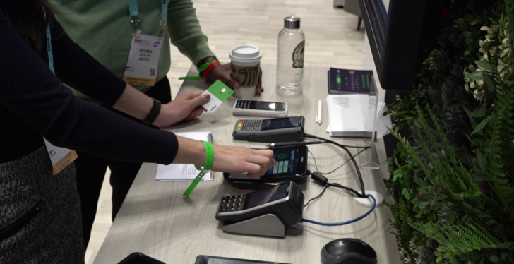 A woman operates a payment device and holds a payment card in her hand;...