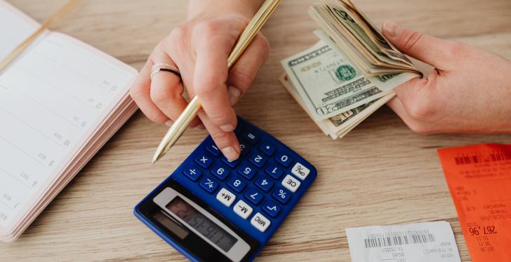 A person using a calculator while holding money