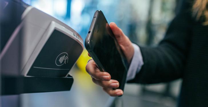 A person holds a smartphone up to a terminal for payment...