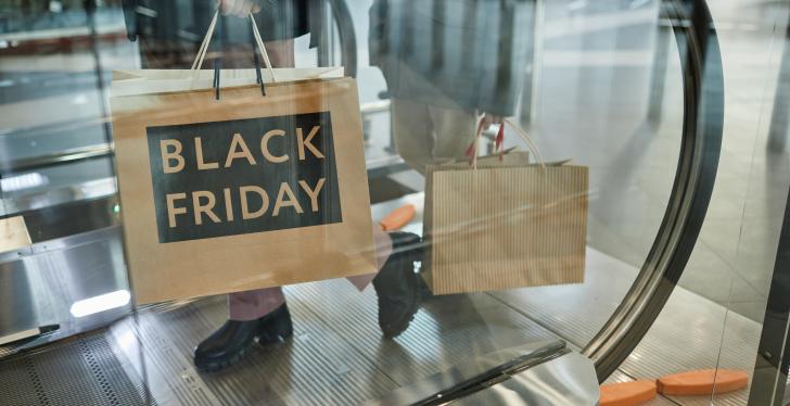 Person with paper bag on an escalator. Writing on the bag. Black Friday...