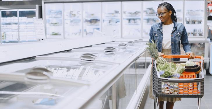 A person stands with a shopping trolley next to a cooling counter...